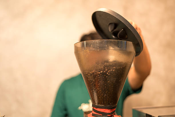 Process of pouring coffee beans into the grinder at coffee shop.