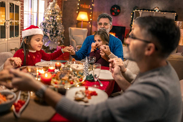 istock Family praying together before Christmas dinner at home 2240260393