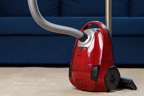 Old and dirty vacuum cleaner in front of the room door on tiled floor at home