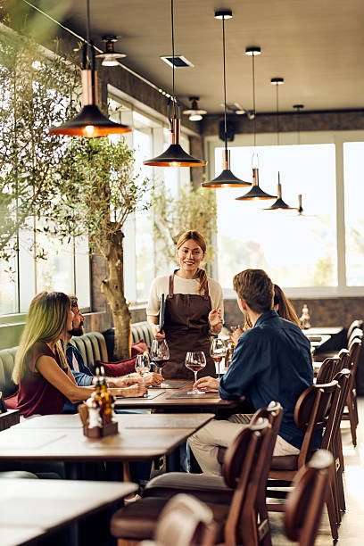 istock Friendly Waitress Serving Drinks to Customers in a Stylish Modern Restaurant Setting 2240261776