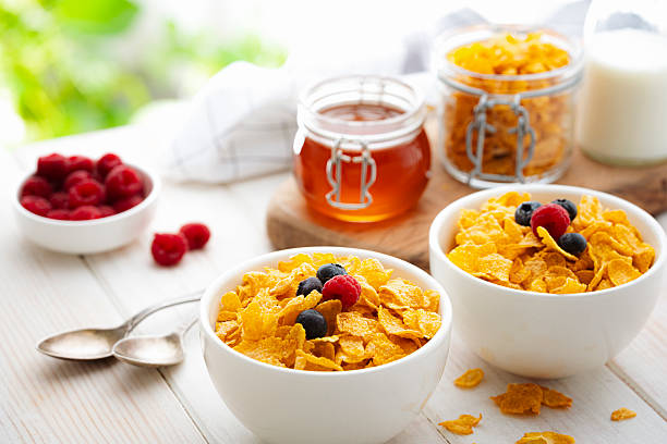 Two bowls filled with corn flakes and berry fruits on white garden table. Breakfast cereal or healthy eating or dieting. Food high in dietary fiber