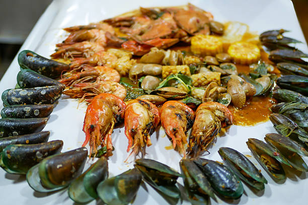 A vibrant seafood platter featuring shrimp, mussels, shellfish, corn and a savory sauce, arranged for an elegant feast.