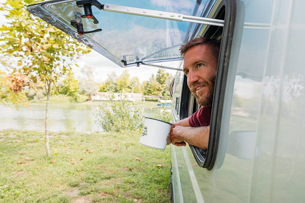 istock Man Leaning Out Camper Van Window Holding a Mug 2240264676