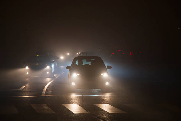 Cars driving slowly in thick fog with plenty of copy space.