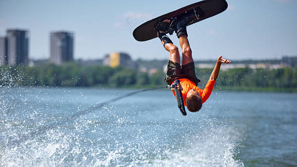 istock Boy wakeboarder upside down flip stunt on river in bright orange shirt 2240271688