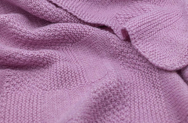 istock Purple knit fabric as a background. Wool knit texture. Purple knitted fabric surface with soft folds. Textile material for design. Purple knitted texture. 2240272445