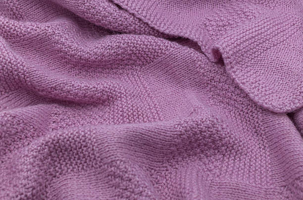istock Purple knit fabric as a background. Wool knit texture. Purple knitted fabric surface with soft folds. Textile material for design. Purple knitted texture. 2240272451