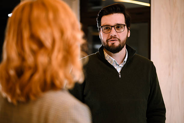 istock Man engages in conversation with a woman in a modern indoor setting during evening hours 2240272562