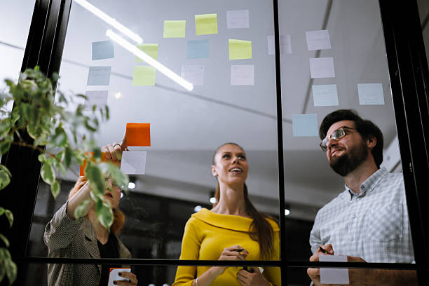 istock Team collaboration during brainstorming session in modern office space with colorful sticky notes on glass wall 2240272565