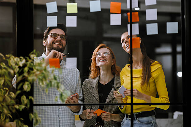 istock Team brainstorming session in modern office space with colorful sticky notes on glass wall in the afternoon light 2240272608