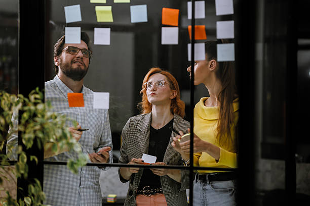 istock Team members brainstorming ideas during a creative meeting in a modern office space with colorful sticky notes on the wall 2240272610