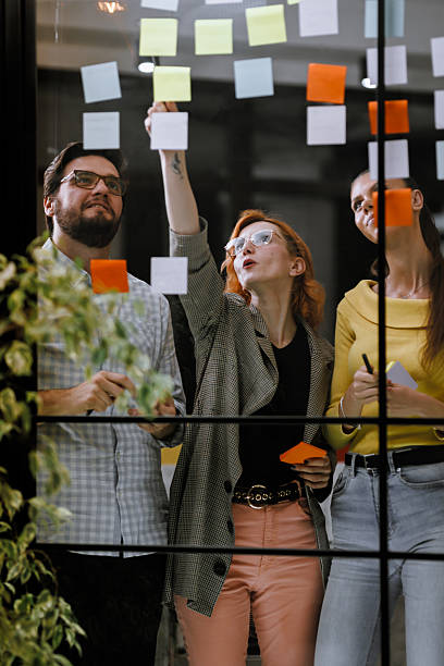istock Team brainstorming session with colorful sticky notes on a glass wall in a modern office setting 2240272612