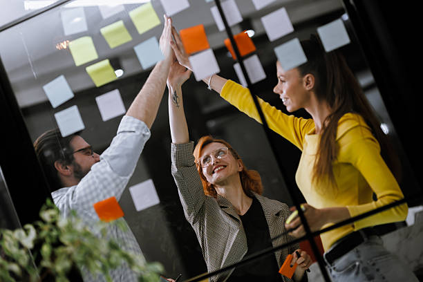 istock Team collaboration is celebrated with high fives and sticky notes in a bright office during a brainstorming session in the afternoon 2240272624