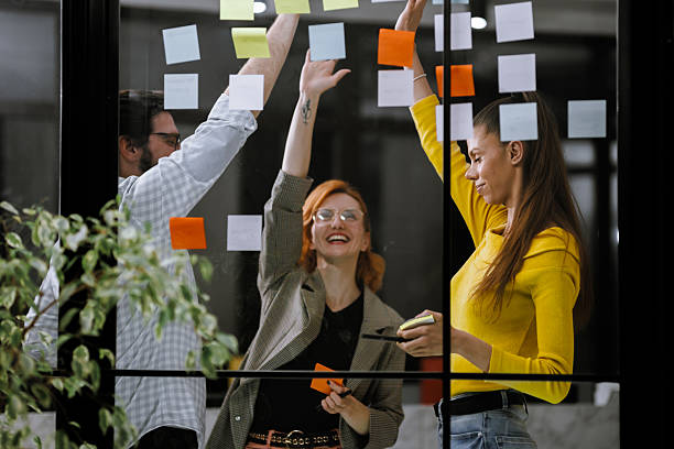 istock Team brainstorming session in a modern office with colorful sticky notes on the windows 2240272625