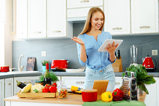 istock Young beautiful caucasian woman cooking and using her digital tablet in kitchen 2240274302