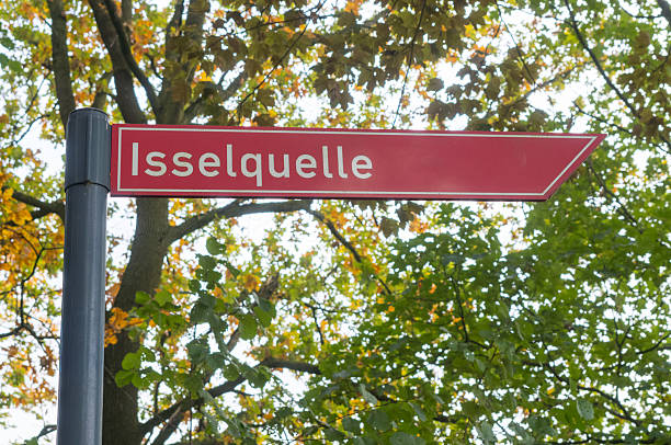 Red directional sign displaying isselquelle in a natural setting, raesfeld, germany