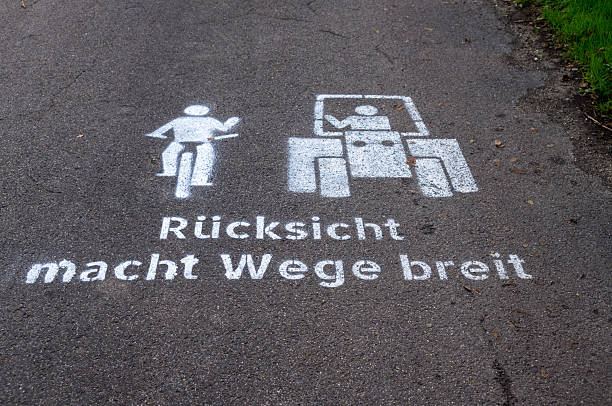 Road stencil on asphalt displaying courtesy motto for cyclists and tractor drivers