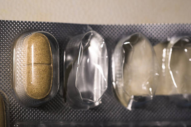 A close-up image shows a blister pack of brown pills, with some compartments empty, suggesting use. The pharmaceutical product is intact in its packaging, highlighting health and medicine concepts. The macro shot emphasizes the pill's texture and protective packaging.