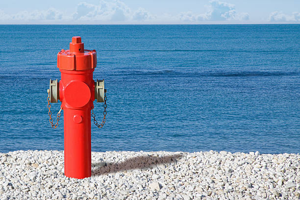 istock RED FIRE HYDRANT ON COAST SYMBOLIZES SAFETY AND CONTRAST - Concept image about protection, isolation, emergency, and resilience with sea and blue sky background 2240281686