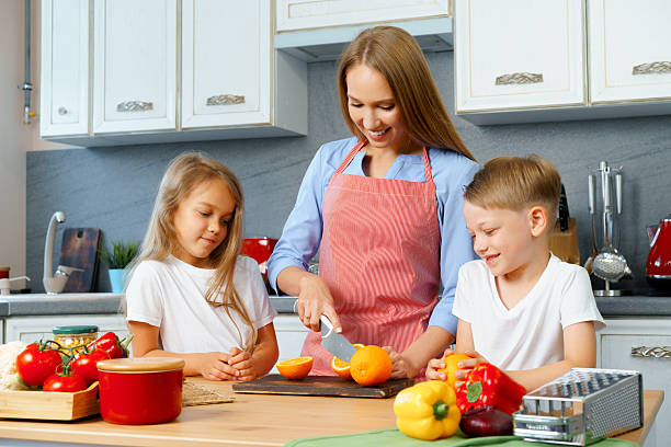 istock Mother cooking with her children in kitchen 2240282667