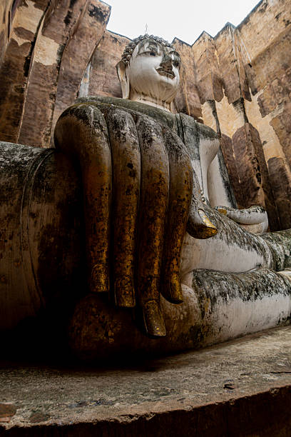 Monumental Buddha image Phra Atchana in subduing mara posture at Wat Sri Chum temple Sukhothai Historical Park, ancient stuccoed brick sculpture, thailand cultural heritage landmark