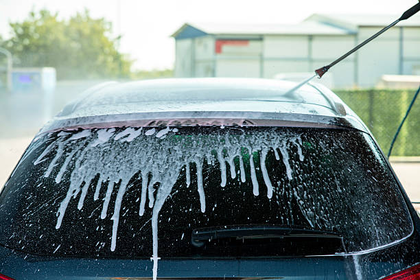 Cleaning a car windshield glass with water high-pressure spray in a self-service car wash