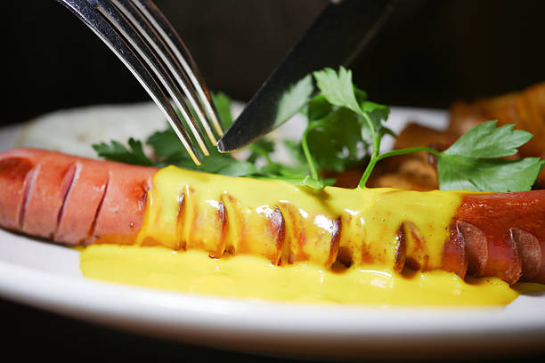 Enjoying a flavorful hot dog topped with mustard and herbs at dinner