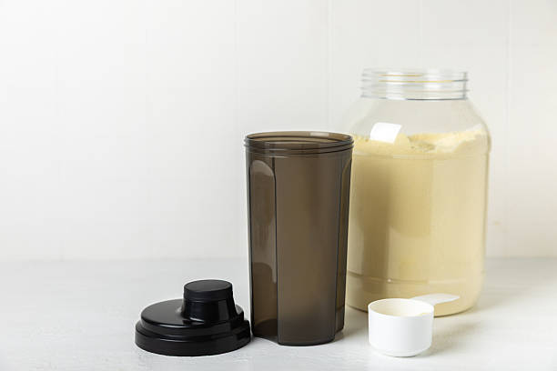 istock Protein shake with protein powder on a colored background. The powder is mixed with water or milk. A dietary supplement for a balanced diet. Whey protein. Fitness and gym diet nutrition. 2240290015
