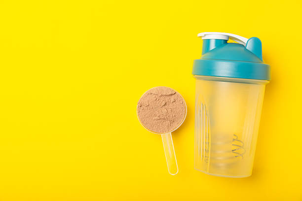 istock Protein shake with protein powder on a colored background. The powder is mixed with water or milk. A dietary supplement for a balanced diet. Whey protein. Fitness and gym diet nutrition. 2240290063