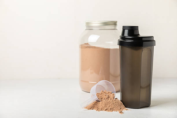 istock Protein shake with protein powder on a colored background. The powder is mixed with water or milk. A dietary supplement for a balanced diet. Whey protein. Fitness and gym diet nutrition. 2240290079