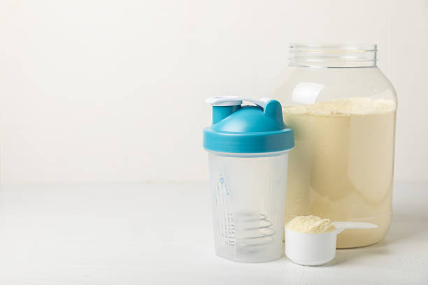 istock Protein shake with protein powder on a colored background. The powder is mixed with water or milk. A dietary supplement for a balanced diet. Whey protein. Fitness and gym diet nutrition. 2240290083