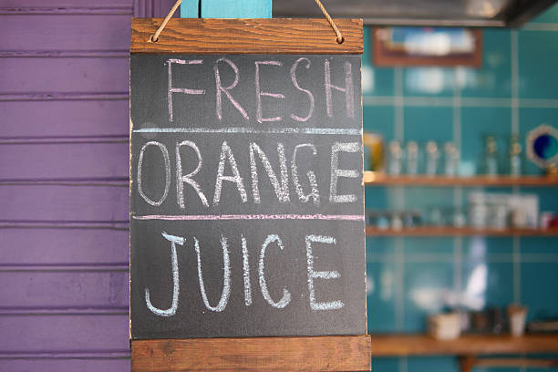 A vibrant sign invites customers to enjoy fresh orange juice.