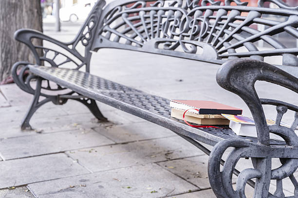 A cast iron bench placed on a city street with a few books to distract you