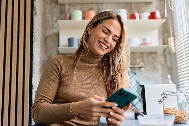 istock Woman smiling and using smartphone during breakfast in kitchen 2240292773