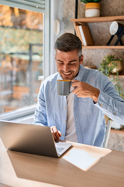 istock Man drinking coffee and working on laptop at home 2240292886