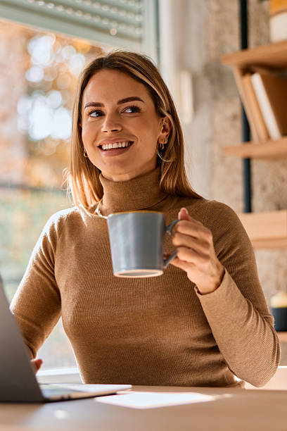 istock Happy woman drinking coffee while working from home 2240292901