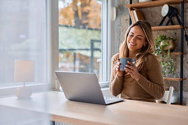 istock Woman drinking coffee and working on laptop at home 2240292922