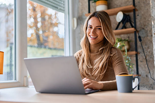 istock Young woman smiling while working on laptop at home 2240292926