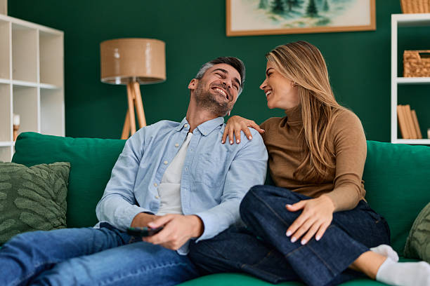 istock Happy couple relaxing on sofa and laughing at home 2240292969
