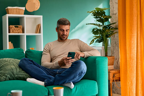 istock Man relaxing on sofa using smartphone in living room 2240293509