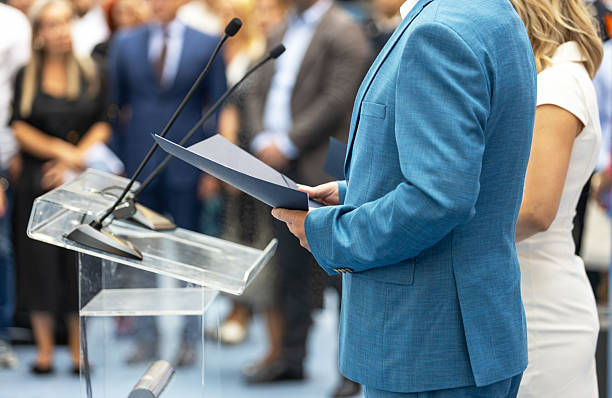 istock Public speaker giving presentation at business or political conference with blurred audience in background, showing leadership, communication, teamwork, and professional public speaking concept 2240296965