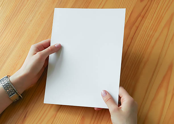 istock Hands holding a blank white paper sheet on a wooden table 2240297374