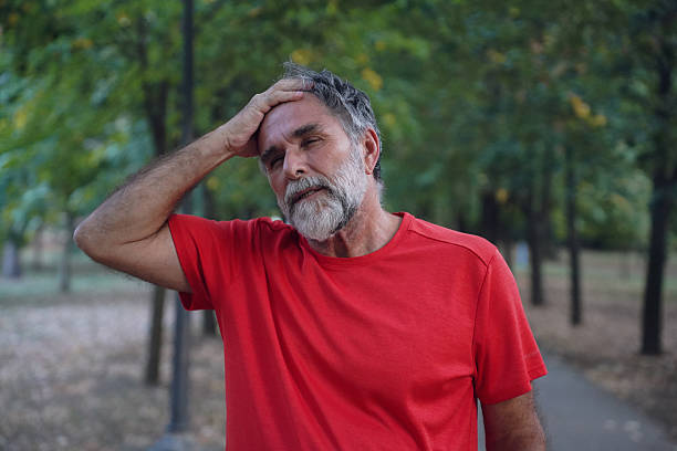 istock Senior Man Experiencing Neck, Head, and Eye Pain While Outdoors in the Park 2240298619