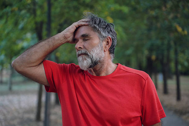 istock Senior Man Experiencing Neck, Head, and Eye Pain While Outdoors in the Park 2240298627
