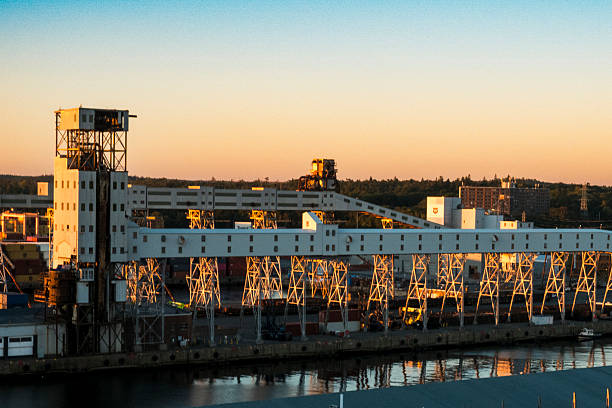 Halifax, NS - CA - Sep 29, 2025 The Halifax Grain Elevator and surrounding port facilities bathed in sunrise light, their reflection mirrored on the calm morning waters.
