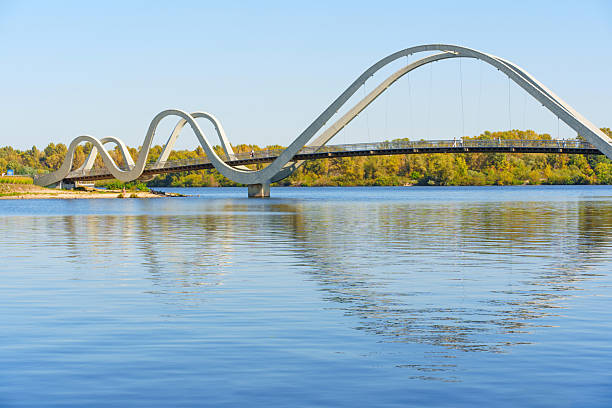 istock Wavy Design Pedestrian Bridge Over Calm Waters in Kyiv with Clear Blue Sky 2240307207