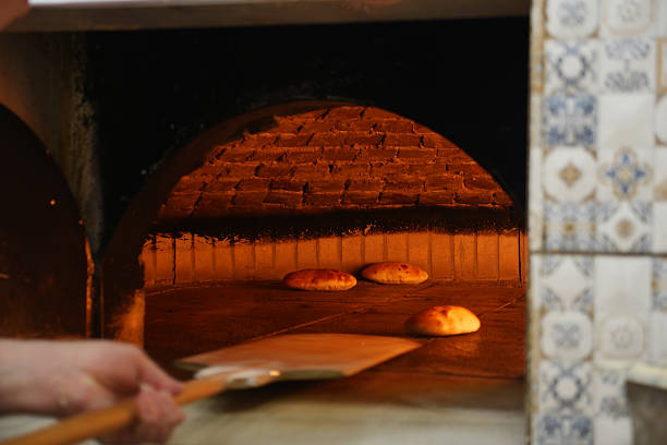 Fresh bread is being baked in a rustic oven, showcasing a warm glow.