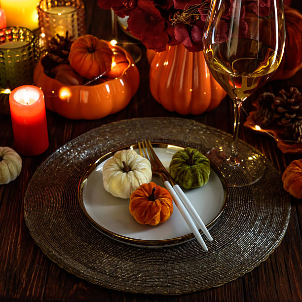 istock Thanksgiving table setting with decorative pumpkins, candles and string lights on dark wooden table 2240309906