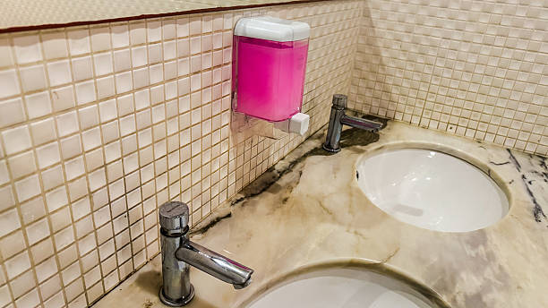 Bathroom sink with liquid soap on the wall