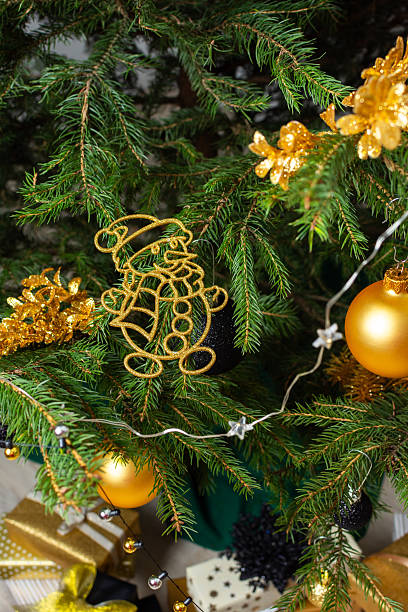 istock Luxurious gold and black gift boxes arranged beneath a Christmas tree, illuminated by glowing candles and adorned with elegant decorations, creating a chic holiday ambiance 2240312790